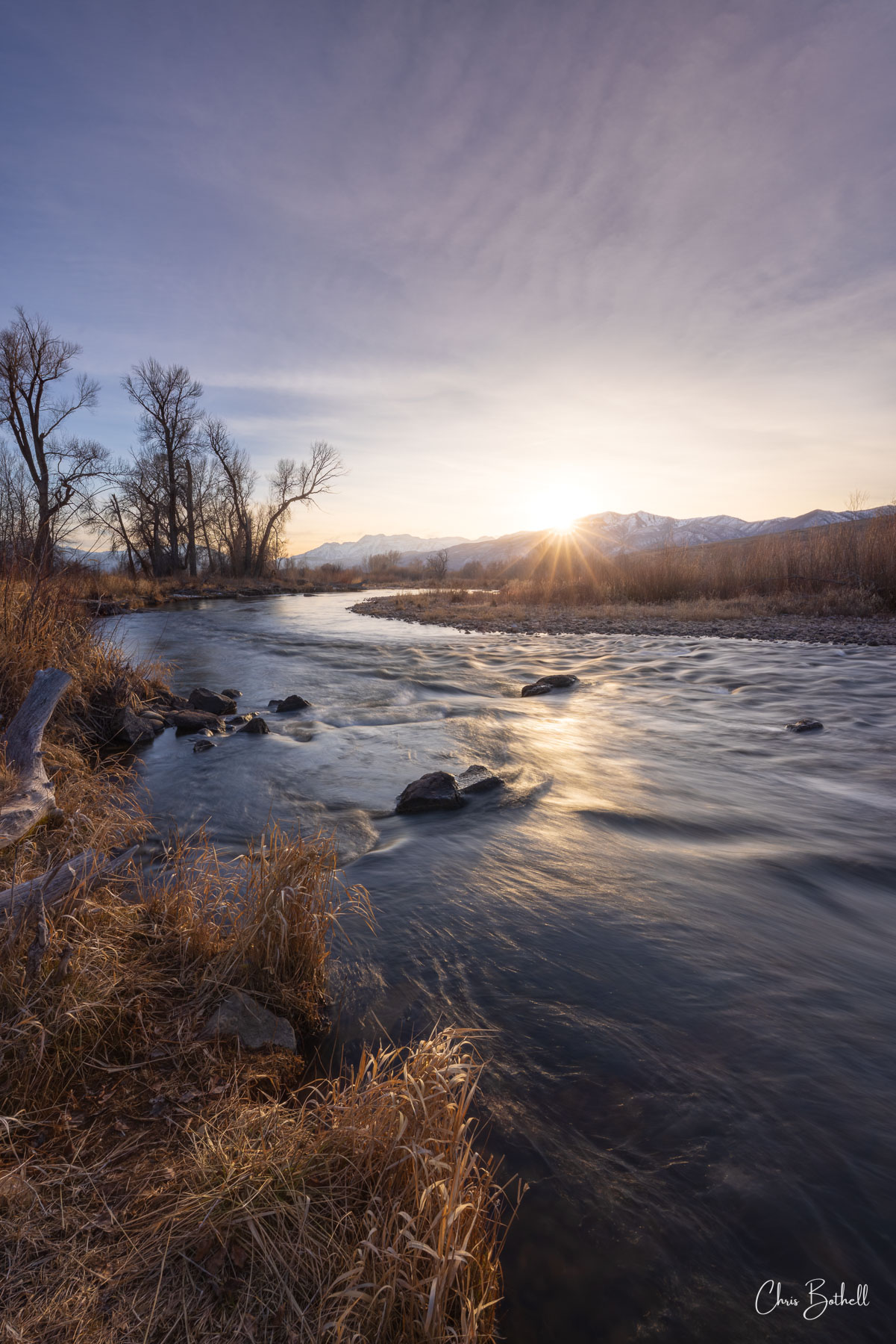 River Ride to Sunset The setting sun crests over the distant peaks, casting a long, liquid gold reflection across the surface of the moving water....